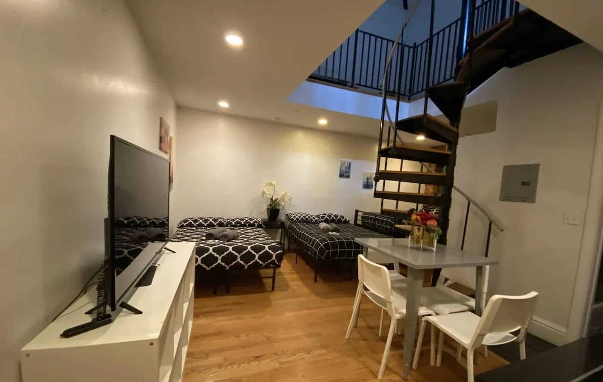 Living area with a TV, table and spiral staircase in one of the hotel's apartments