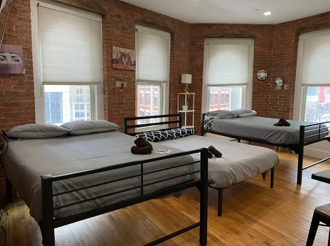Room with three beds and street-facing windows at 31 Street Broadway