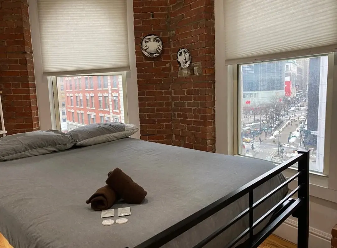 Double bed next to a window with a street view